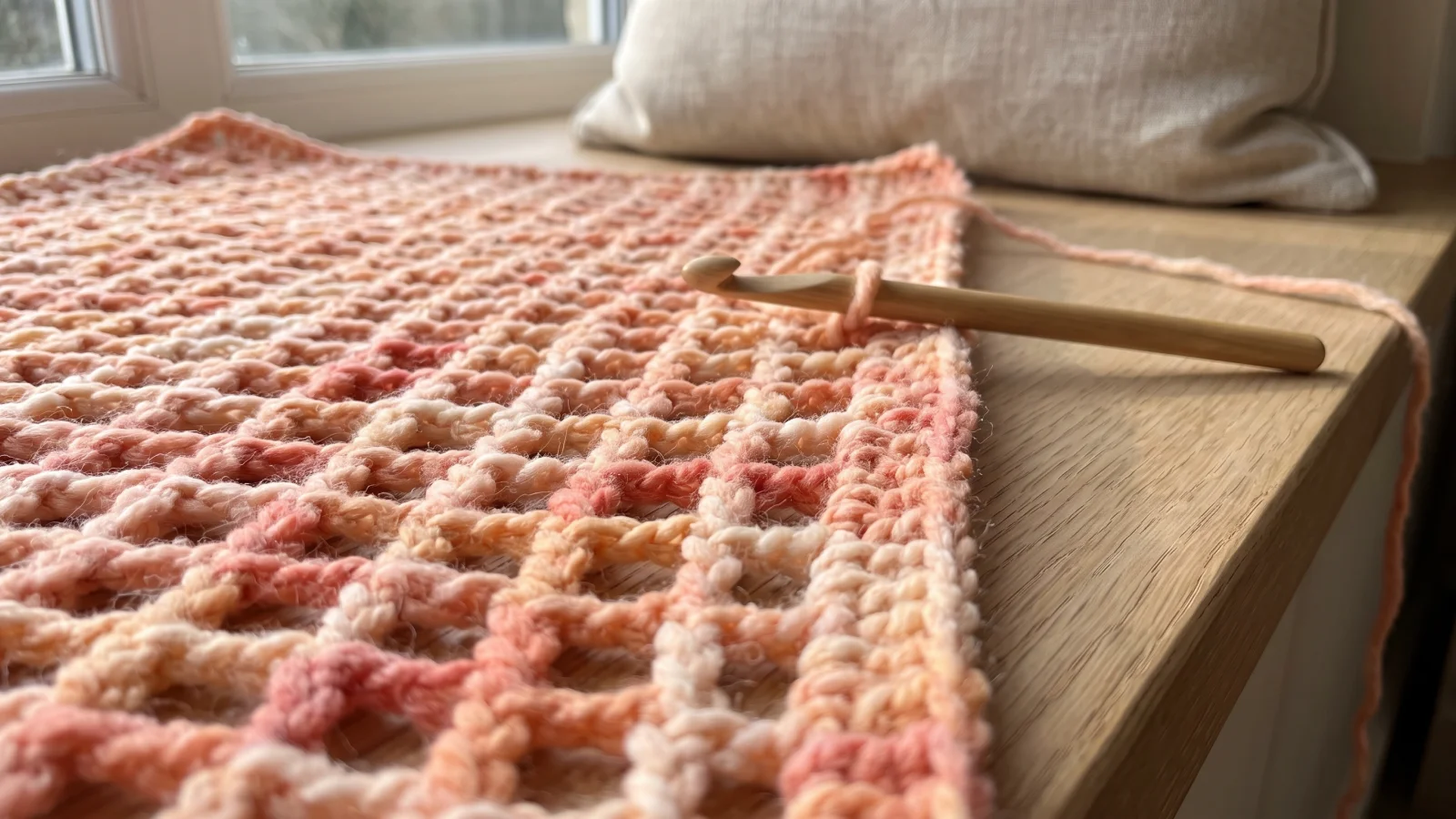 Crochet hook working Row 1 along a long chain, with a few single crochet stitches separated by chain-1 spaces